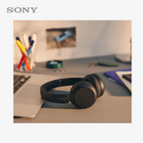 Sony headphones on a desk with a laptop and office supplies in the background