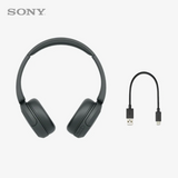 Black wireless headphones with USB cable on a light gray background
